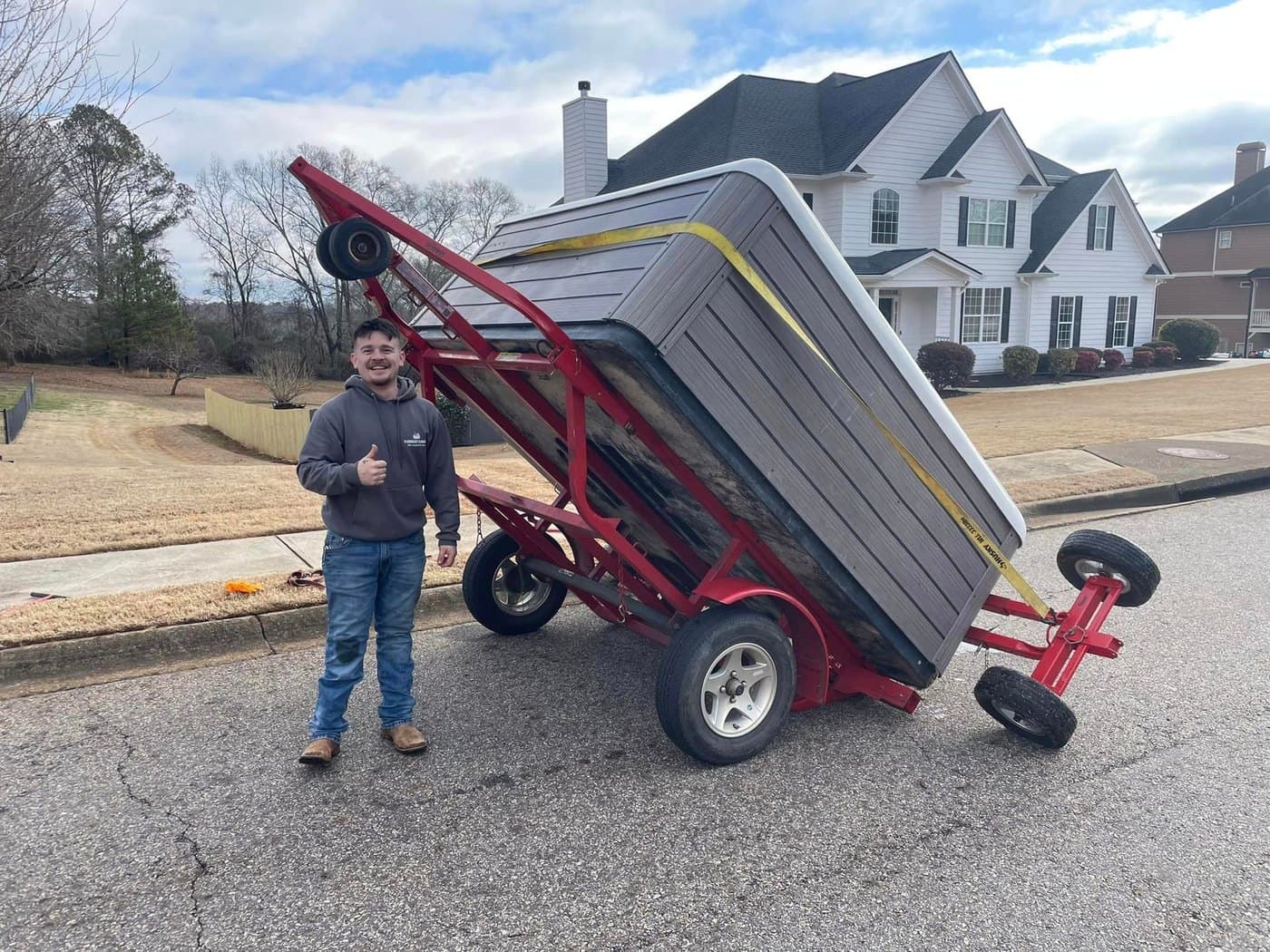 A Platinum crew member smiling beside a hot tub on a specialty trailer-dolly